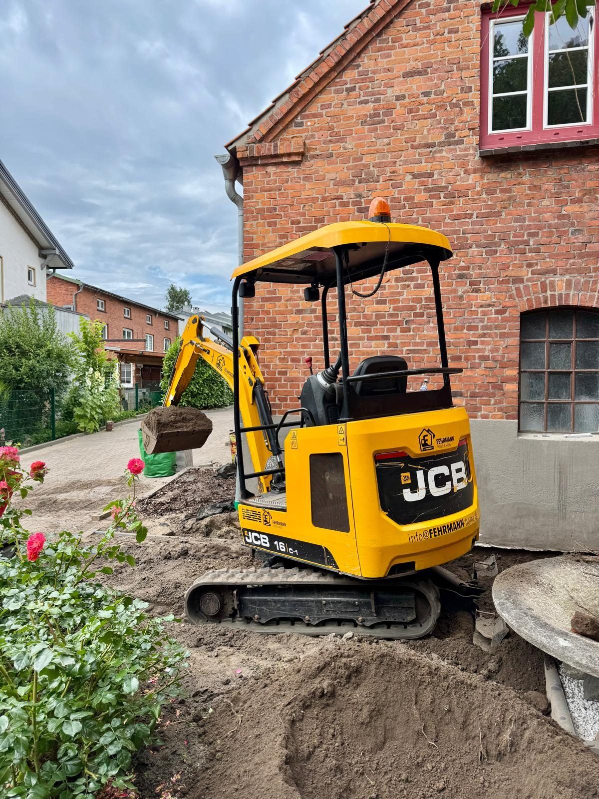 JCB 16C-1 von Fehrmann Home & More beim Aushub direkt neben einem Backsteinhaus