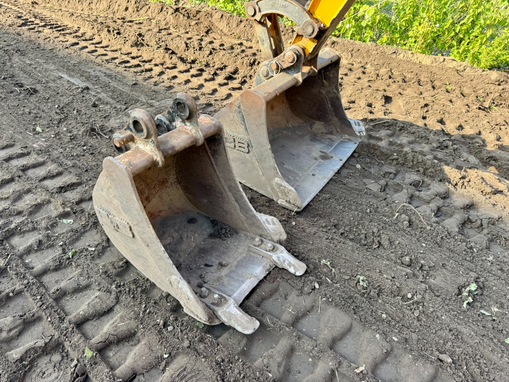 Detailaufnahme von Löffel und Zähnen des JCB 16C-1 im Erdreich